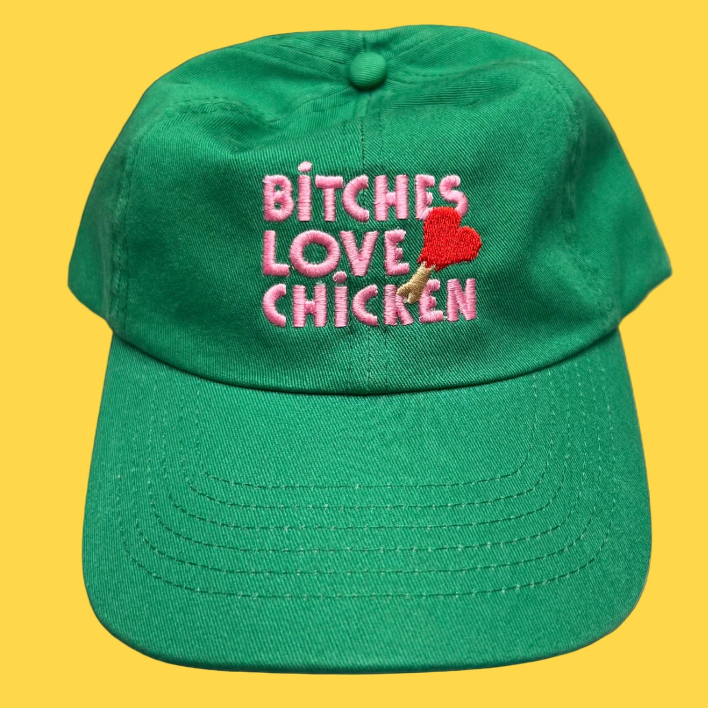 Green hat embroidered with pink text reading “Bitches Love Chicken.”